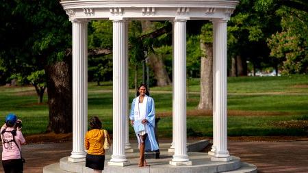 Student in a graduation gown at the Old Well.